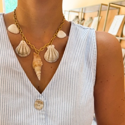 Colar dourado com conchas naturais usado com vestido riscado azul claro e branco