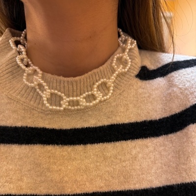 Colar de pérolas com elos grandes em cima de camisola bege com riscas pretas