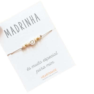 Pulseira com contas e coração em cartão branco com texto em português.