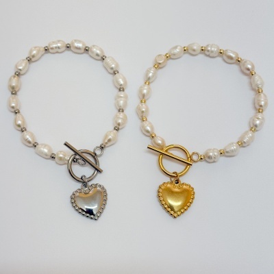 Duas pulseiras de pérolas com fecho e pendente de coração, uma prateada e outra dourada
