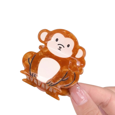 Prendedor de cabelo acrílico formato macaco castanho claro e bege.