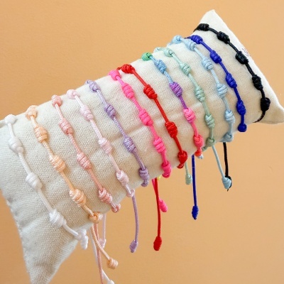 Pulseiras coloridas de corda com nós em almofada branca
