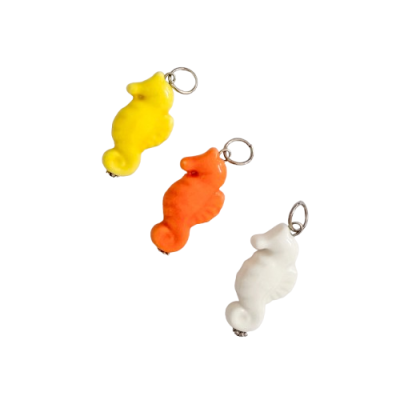 Três pendentes em forma de cavalo-marinho em amarelo, laranja e branco com argolas metálicas