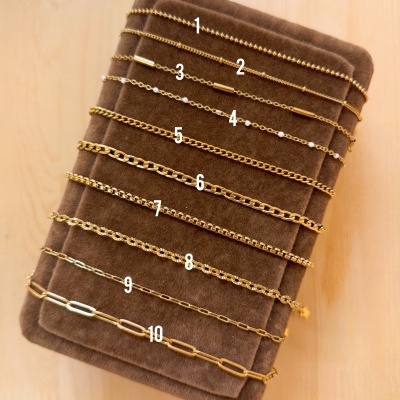 Dez pulseiras finas douradas e prateadas numeradas em suporte de veludo castanho claro