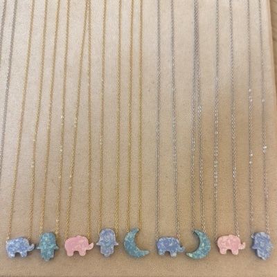 Colares com pendentes coloridos de formas variadas sobre fundo bege