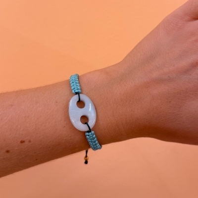 Pulseira com cordão azul turquesa e pendente oval de pedra branca num pulso