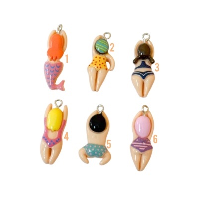 Seis pingentes coloridos representando mulheres de costas em maiôs e uma sereia, cada um com argola metálica.
