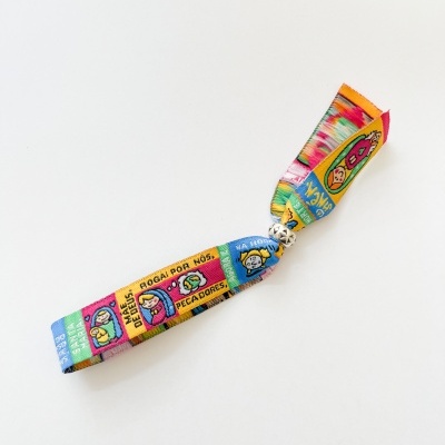 Pulseira de tecido colorida com texto e pequeno fecho metálico sobre fundo branco