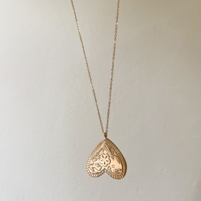 Colar dourado com pendente em forma de coração com padrão floral e textura gravada
