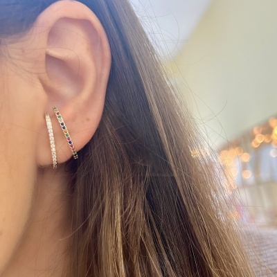 Duas argolas coloridas no lóbulo da orelha feminina