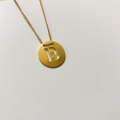Colar dourado com pendente redondo e letra B recortada