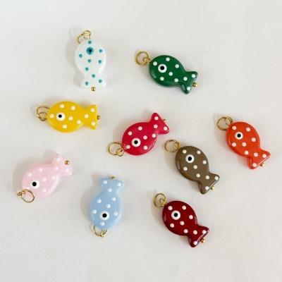 Pingentes coloridos em forma de peixe com pintas brancas e olhos desenhados, sobre fundo branco.