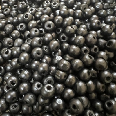 Contas esféricas pretas com furos centrais sobre fundo texturizado bege