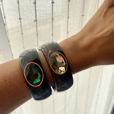 Pulseiras de plástico preto com pedras grandes facetadas verde e bege no pulso