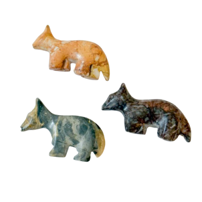 Esculturas pequenas de raposas em pedra polida, em três cores diferentes.