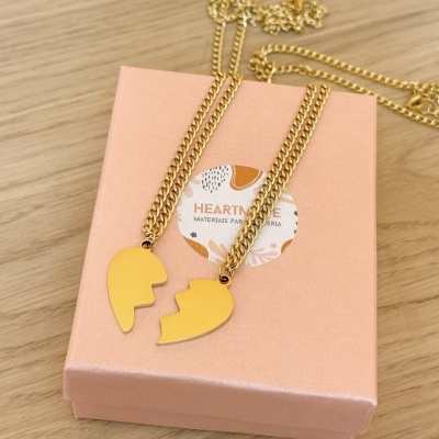 Colar dourado com pendentes de coração partido em caixa rosa