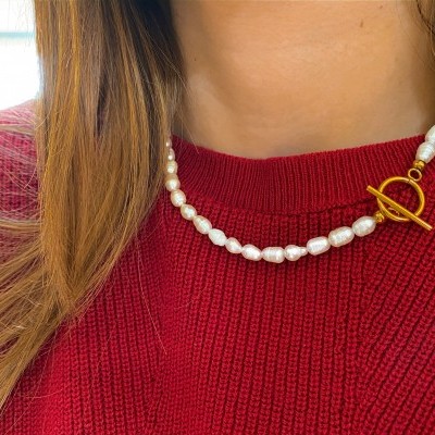 Gargantilha de pérolas brancas com fecho dourado em pescoço e camisola vermelha