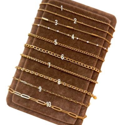 Conjunto de 10 pulseiras douradas em suporte de veludo castanho numeradas de 1 a 10