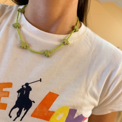 Colar verde com elefantes em conta usado com t-shirt branca estampada