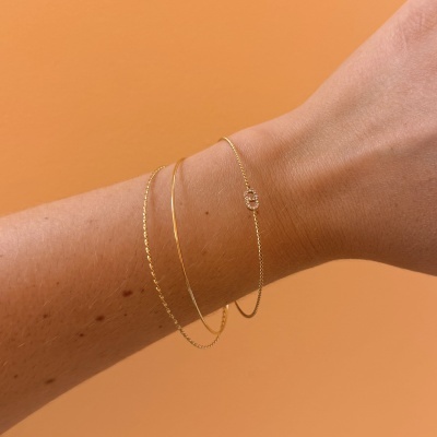 Pulseira fina dourada com pendente brilhante no pulso de uma pessoa