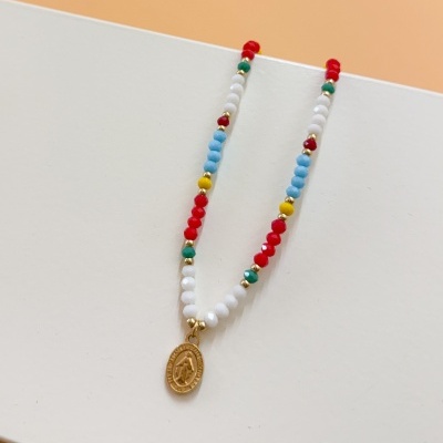 Colar com contas coloridas e pendente dourado sobre fundo branco e laranja