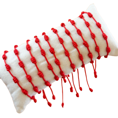 Pulseiras vermelhas artesanais expostas em almofada branca texturizada