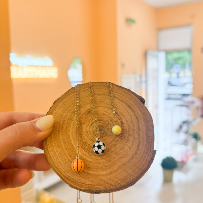 Colares com pendentes de bolas desportivas exibidos em placa de madeira
