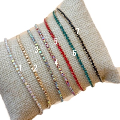 Sete pulseiras coloridas numeradas sobre almofada bege