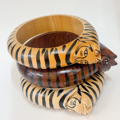 Três pulseiras de madeira pintadas com padrão de tigre.