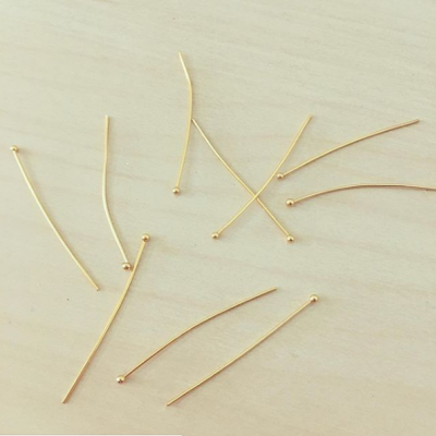 Alfinetes dourados com cabeça redonda sobre superfície clara