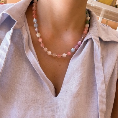 Colar de contas coloridas em tons pastel e esferas metálicas, usado com camisa lilás.