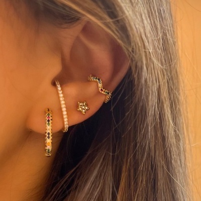 Orelha feminina com três brincos dourados e pedras coloridas