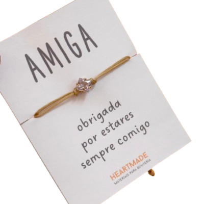 Pulseira dourada com pedra transparente em cartão branco com texto em português