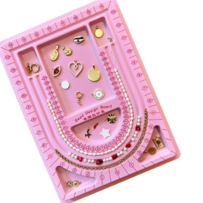 Tabuleiro rosa para design de bijuteria com peças douradas e pérolas falsas