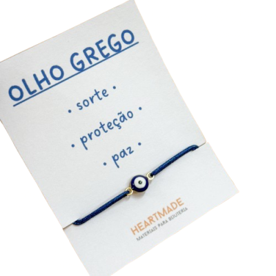 Pulseira azul com pendente de olho grego em cartão branco com texto descritivo