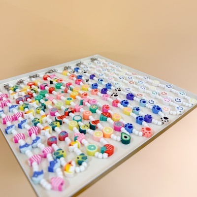 Pulseiras coloridas com contas de plástico em formas diversas numa bandeja branca