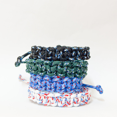 Pulseiras trançadas coloridas em preto, verde, azul e branco empilhadas