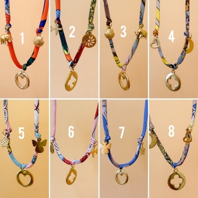 Oito colares coloridos com pendentes dourados dispostos em duas fileiras numeradas de 1 a 8