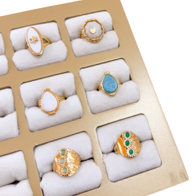 Conjunto de anéis dourados com pedras coloridas apresentados em estojo bege
