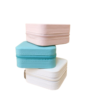 Três caixas de armazenamento têxtil com zíper em cores rosa, azul e branca empilhadas