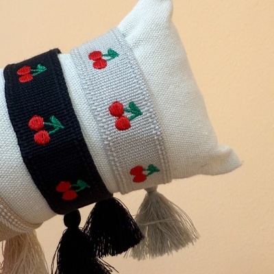 Braceletes tecidos com padrão de cereja e franjas em suporte branco
