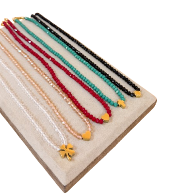 Sete pulseiras coloridas com pendentes dourados sobre base de veludo bege