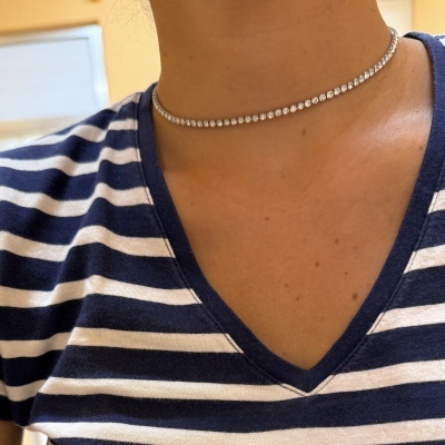 Gargantilha com pedras brilhantes em pessoa com t-shirt às riscas azul e branco