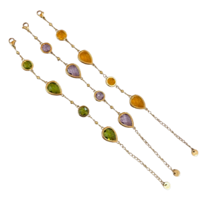 Três pulseiras finas com pedras coloridas verde, lilás e âmbar e fechos dourados.