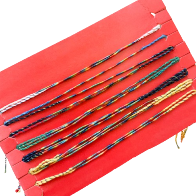 Oito pulseiras trançadas coloridas sobre cartão vermelho