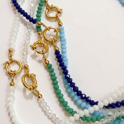 Pulseiras de contas coloridas com fechos dourados sobre fundo branco