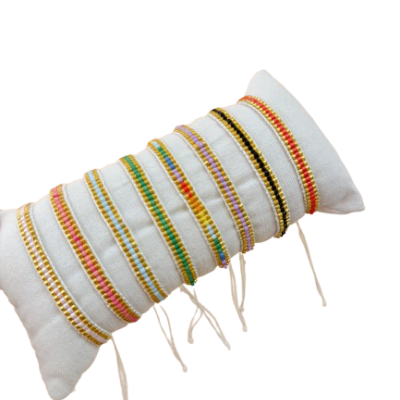 Pulseiras artesanais coloridas exibidas em almofada branca