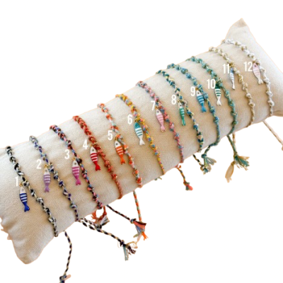 Duas dezoito pulseiras coloridas com peixes em madeira sobre almofada bege