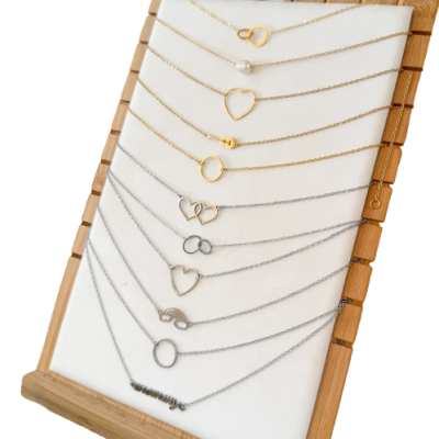Colares delicados dourados e prateados com pendentes variados em suporte branco e moldura de madeira