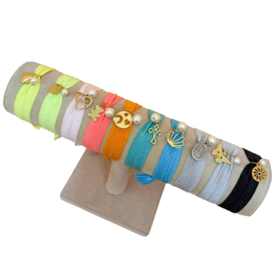 Conjunto de pulseiras elásticas coloridas com pendentes dourados e pérolas em suporte cinzento